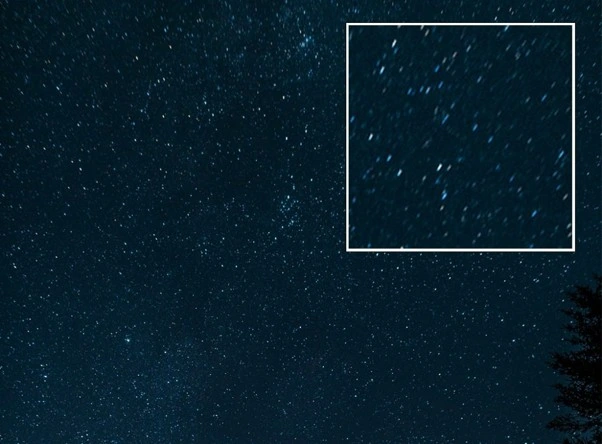 Night sky photograph with stars near the field edge stretched into comet shapes